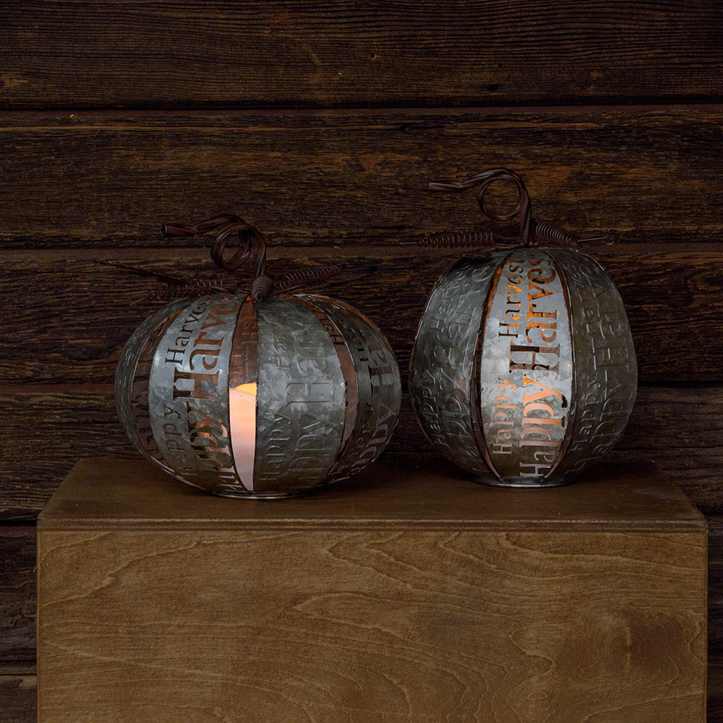 Set of 2 lighted metal pumpkins with a dark wooden background.