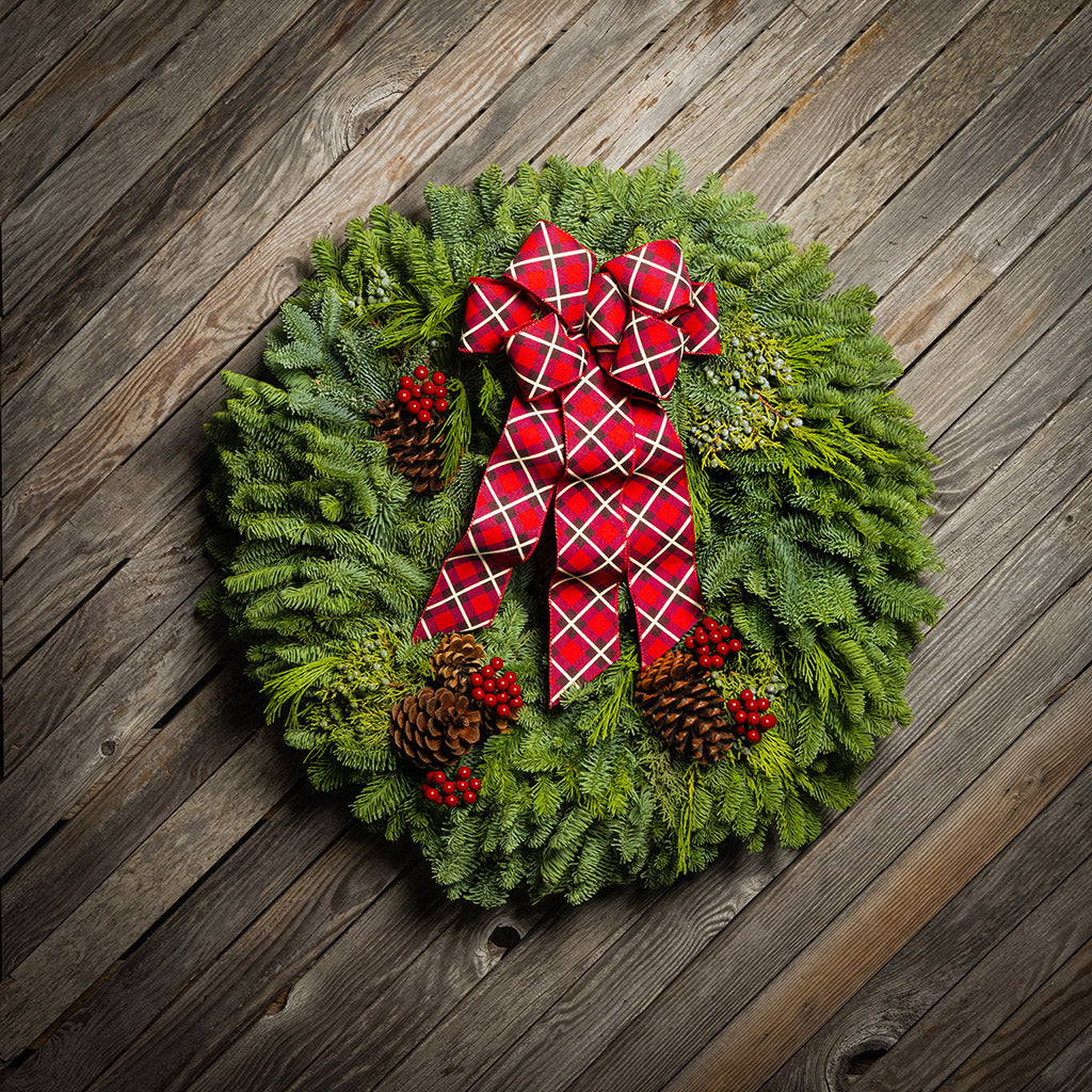 Christmas wreath with a red plaid bow on a wooden background