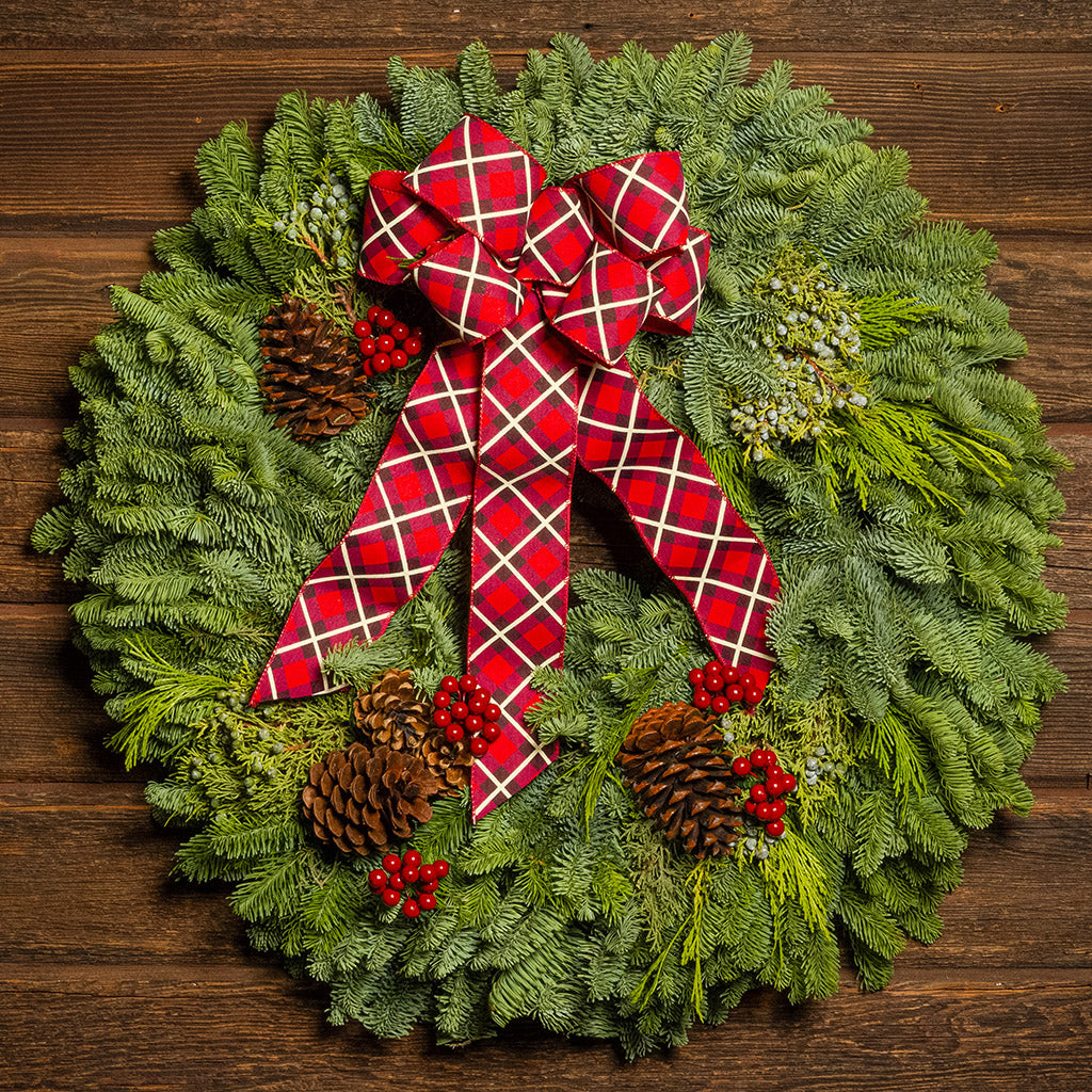 Christmas wreath with a red plaid bow on a wooden background