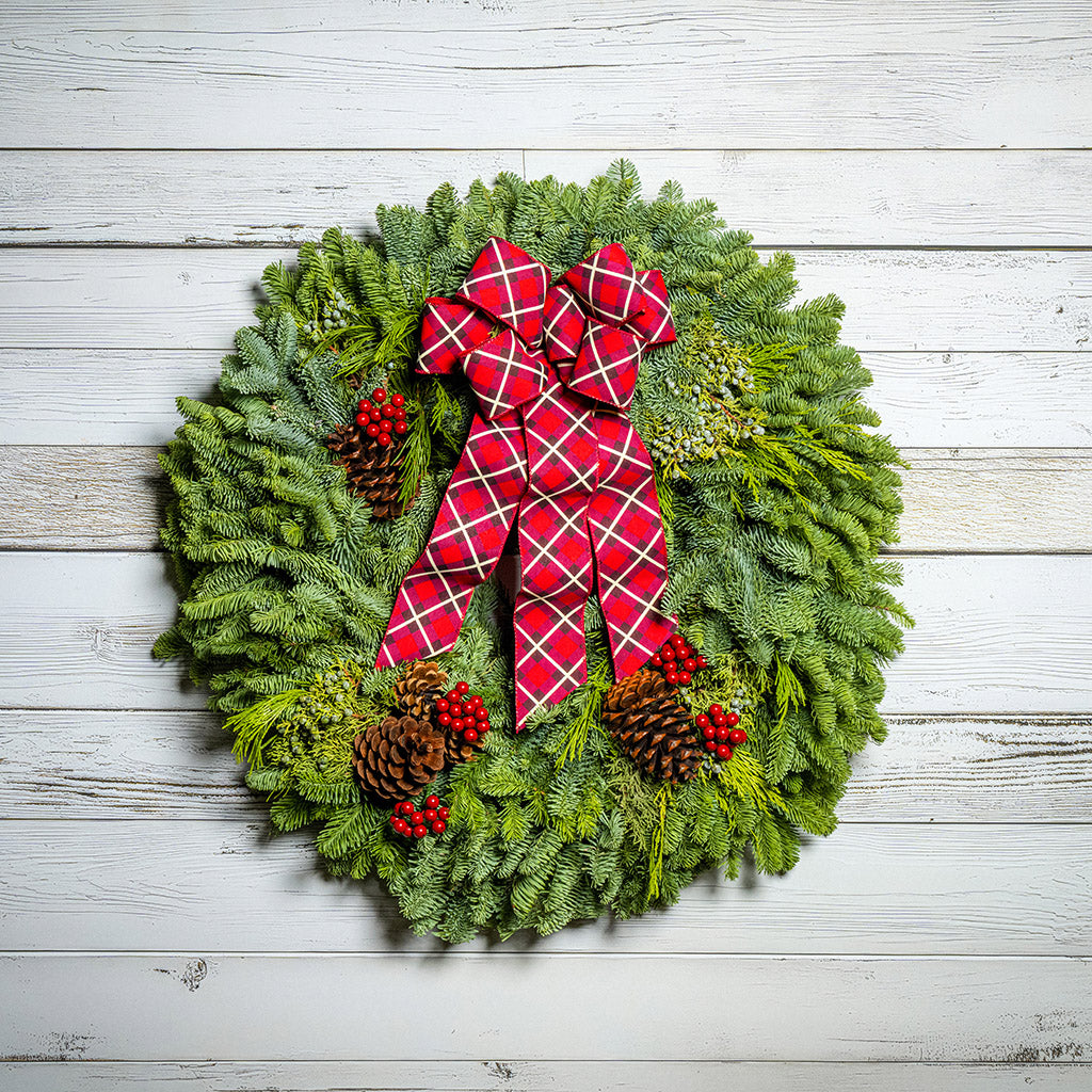Christmas wreath with a red plaid bow on a wooden background