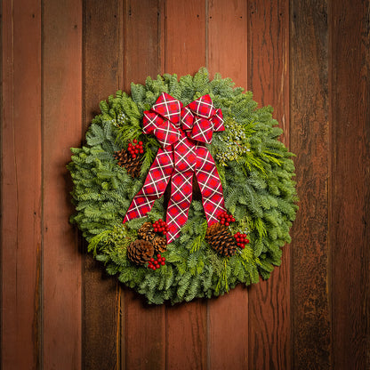 Christmas wreath with a red plaid bow on a wooden door