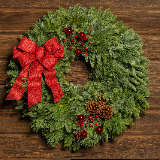 Christmas wreath with red bow and decorations on a wooden background