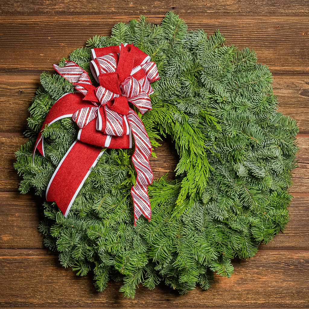 Christmas wreath with a red and white bow on a wooden background
