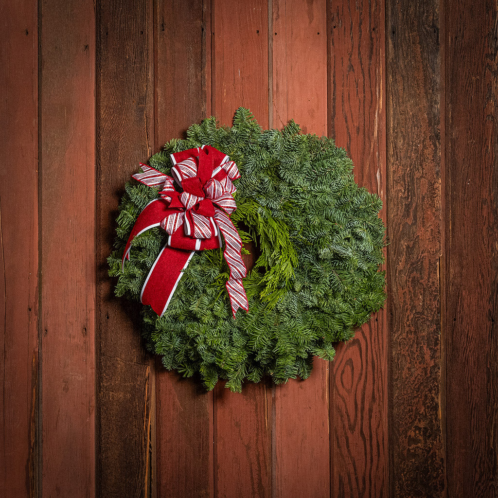 Christmas wreath with a red and white bow on a wooden background