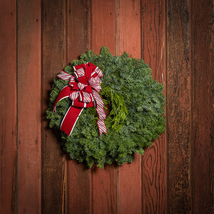 Christmas wreath with a red and white bow on a wooden background