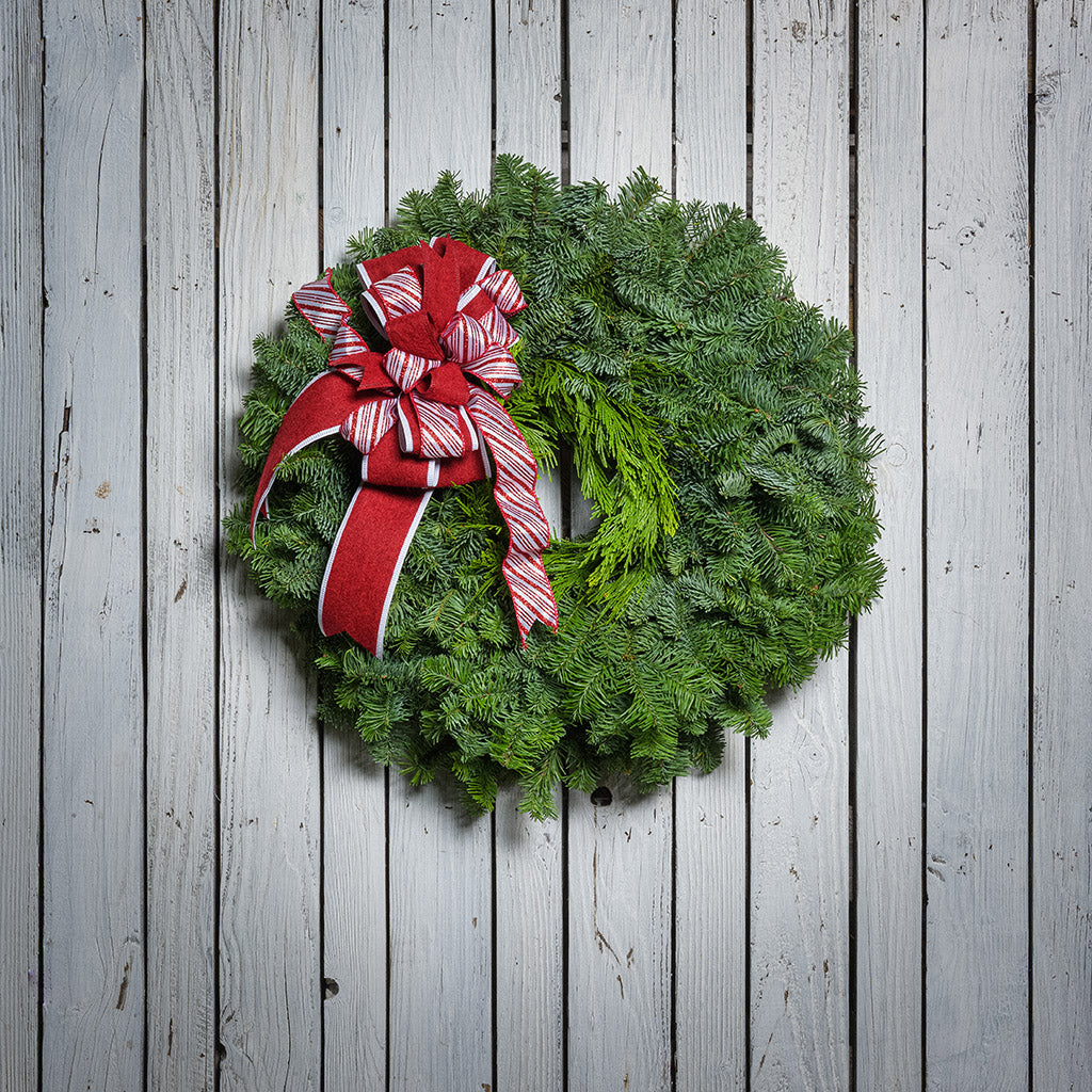 Christmas wreath with a red and white bow on a wooden background