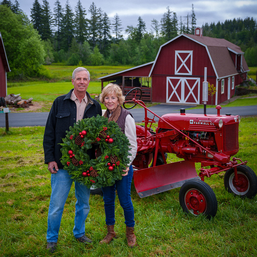 An evergreen wreath of noble fir and cedar with natural pinecones, faux red berries, and red ball ornaments