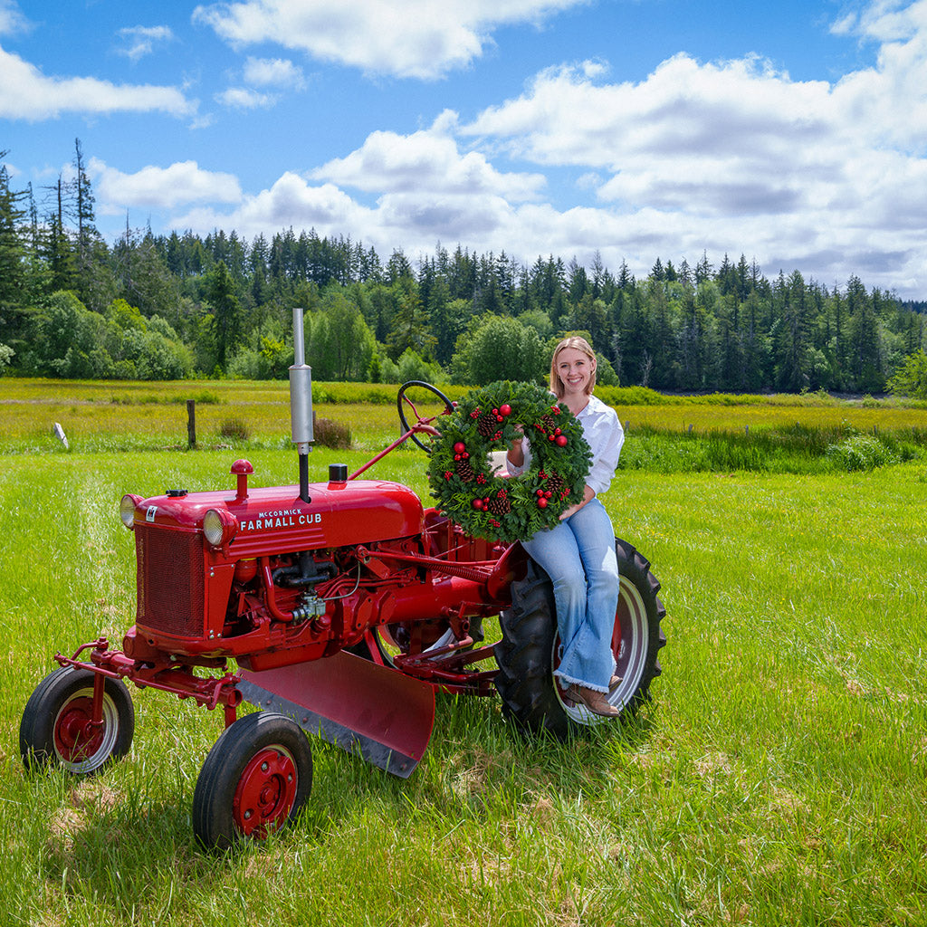 An evergreen wreath of noble fir and cedar with natural pinecones, faux red berries, and red ball ornaments