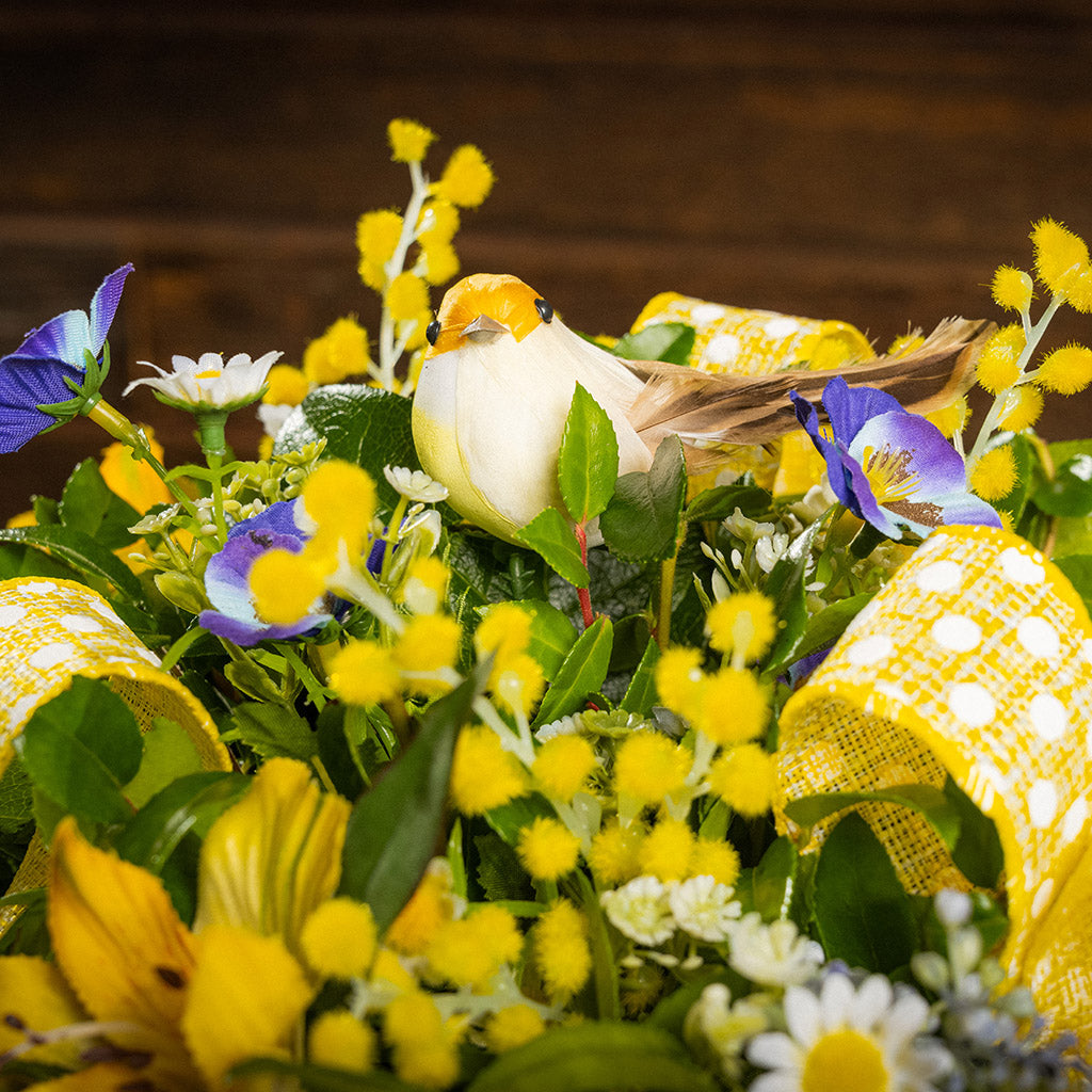 Fresh salal and green huckleberry with faux pansies, and faux yellow Alstromeria lilies, a yellow bird, and yellow polka-dot bows.