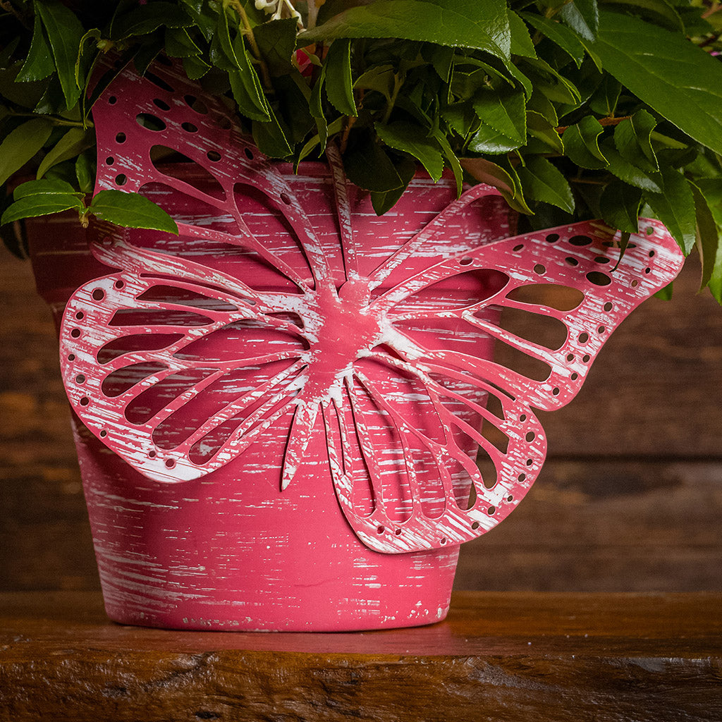 Fresh salal and green huckleberry with faux pink roses and faux pink wildflowers in a pink butterfly-themed metal pot