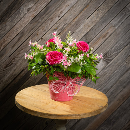 Fresh salal and green huckleberry with faux pink roses and faux pink wildflowers in a pink butterfly-themed metal pot