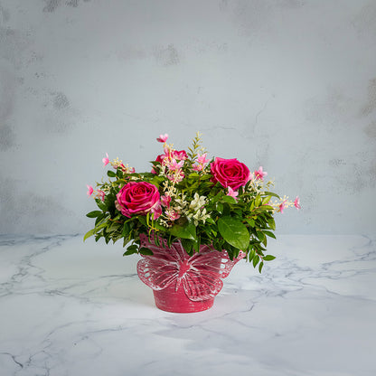 Fresh salal and green huckleberry with faux pink roses and faux pink wildflowers in a pink butterfly-themed metal pot