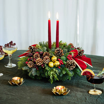 Traditional centerpiece with red balls, pine cones and berries with 2 red velveteen bows and two red taper candles