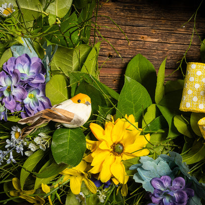 Fresh salal and sweet huckleberry with faux lavender pansies, faux yellow forsythia flowers, faux purple delphinium flowers, faux yellow daisies, and three birds with a yellow polka-dot bow