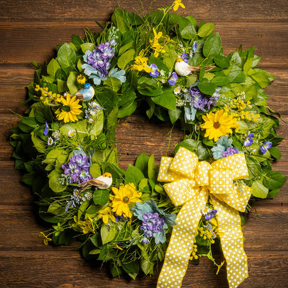 Fresh salal and sweet huckleberry with faux lavender pansies, faux yellow forsythia flowers, faux purple delphinium flowers, faux yellow daisies, and three birds with a yellow polka-dot bow