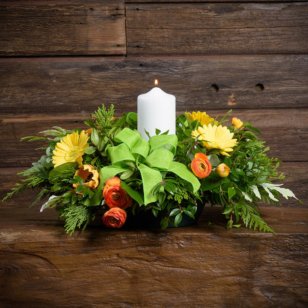 Floral arrangement with a white candle on a wooden surface