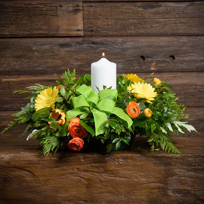 Floral arrangement with a white candle on a wooden surface