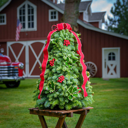 Fresh hand-assembled tabletop Christmas tree with fir, variegated holly, red berries and a red velveteen bow and white LEDs