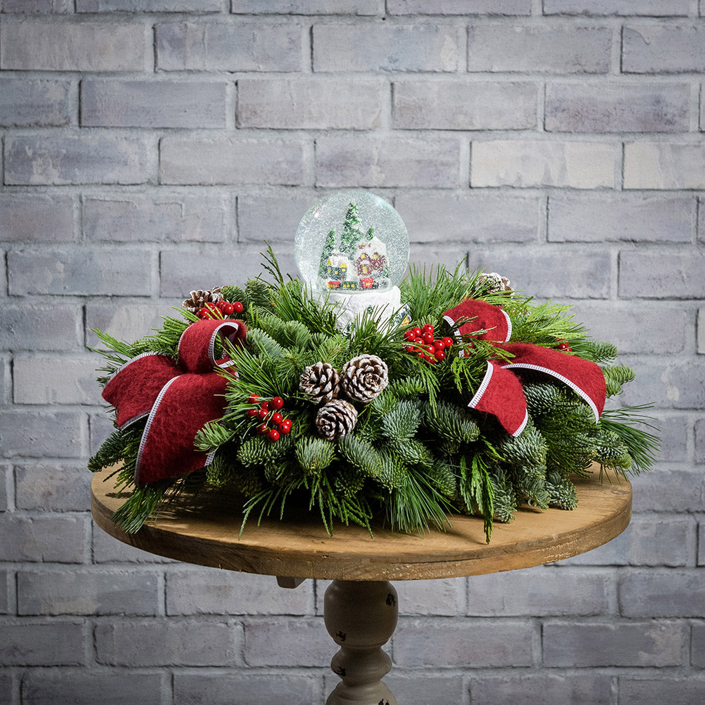 noble fir, cedar, and white pine with frosted pinecones, faux red berries, red brushed-linen bow tucks, and a light-up snowglobe