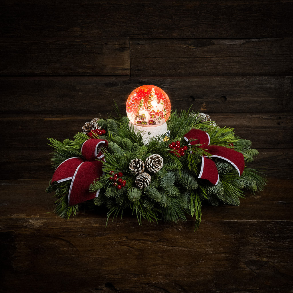 noble fir, cedar, and white pine with frosted pinecones, faux red berries, red brushed-linen bow tucks, and a light-up snowglobe