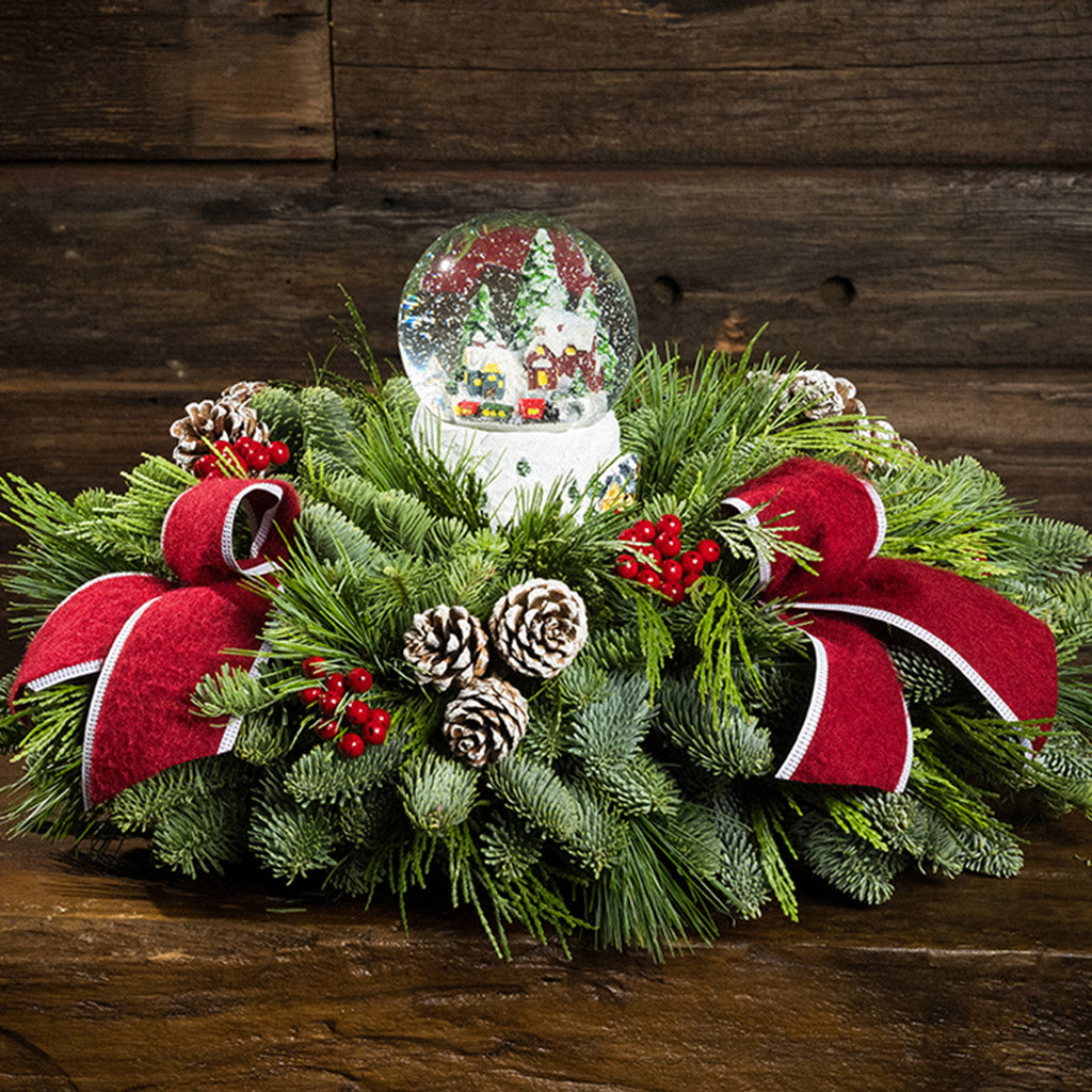 noble fir, cedar, and white pine with frosted pinecones, faux red berries, red brushed-linen bow tucks, and a light-up snowglobe