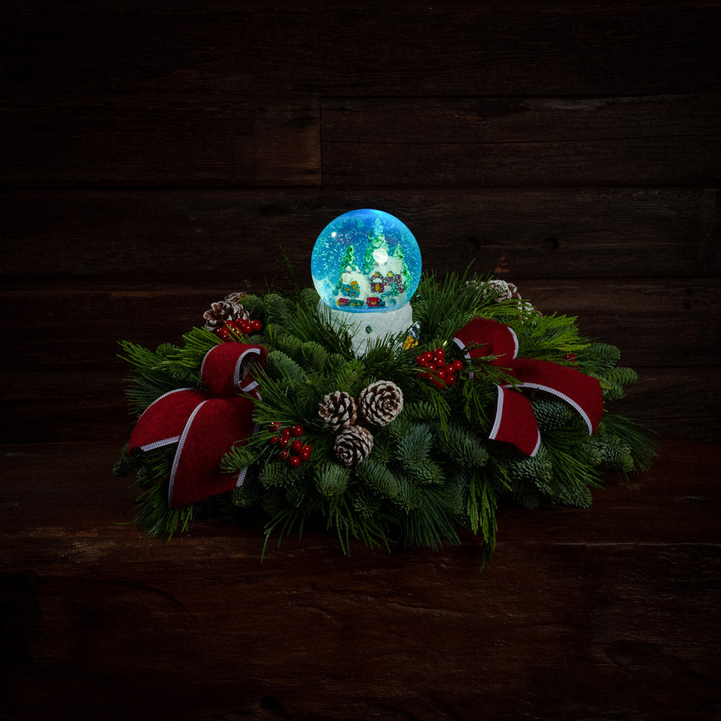 noble fir, cedar, and white pine with frosted pinecones, faux red berries, red brushed-linen bow tucks, and a light-up snowglobe