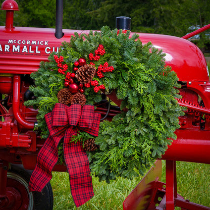 noble fir and cedar with natural pinecones, red ball ornaments, faux red berries, and a 4” wide tartan bow