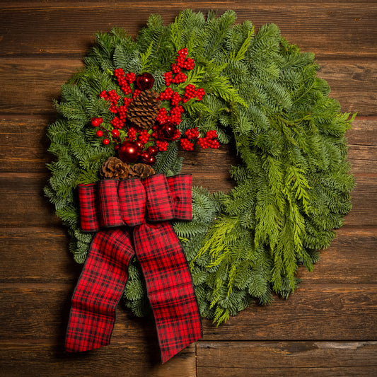 noble fir and cedar with natural pinecones, red ball ornaments, faux red berries, and a 4” wide tartan bow