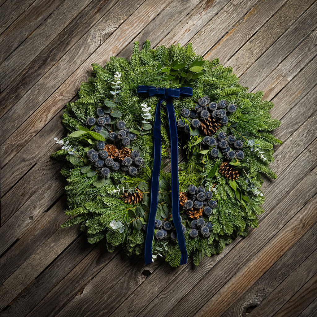 Green wreath with decorative elements on a wooden surface