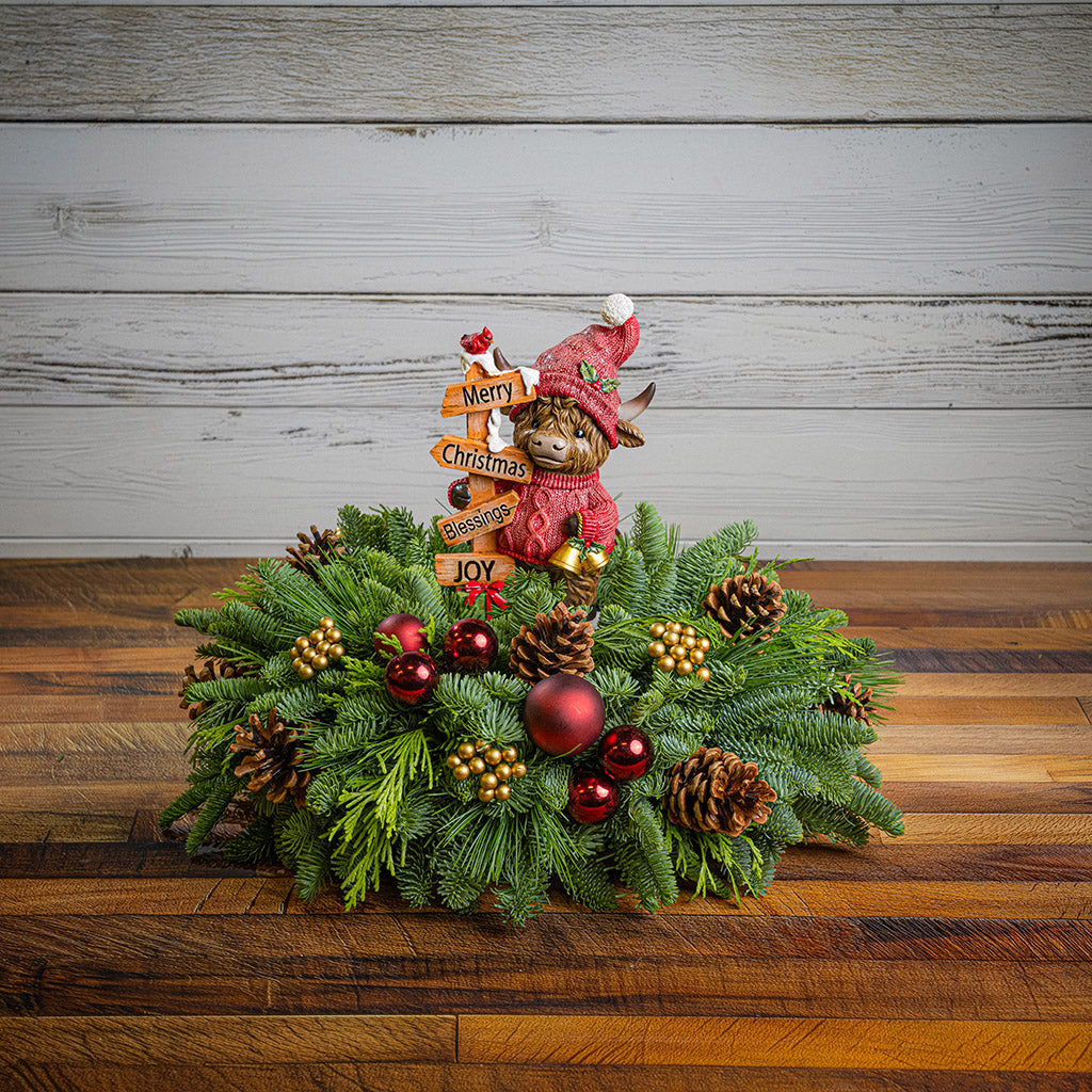 Decorative Christmas wreath with an elf figurine and ornaments on a wooden surface.