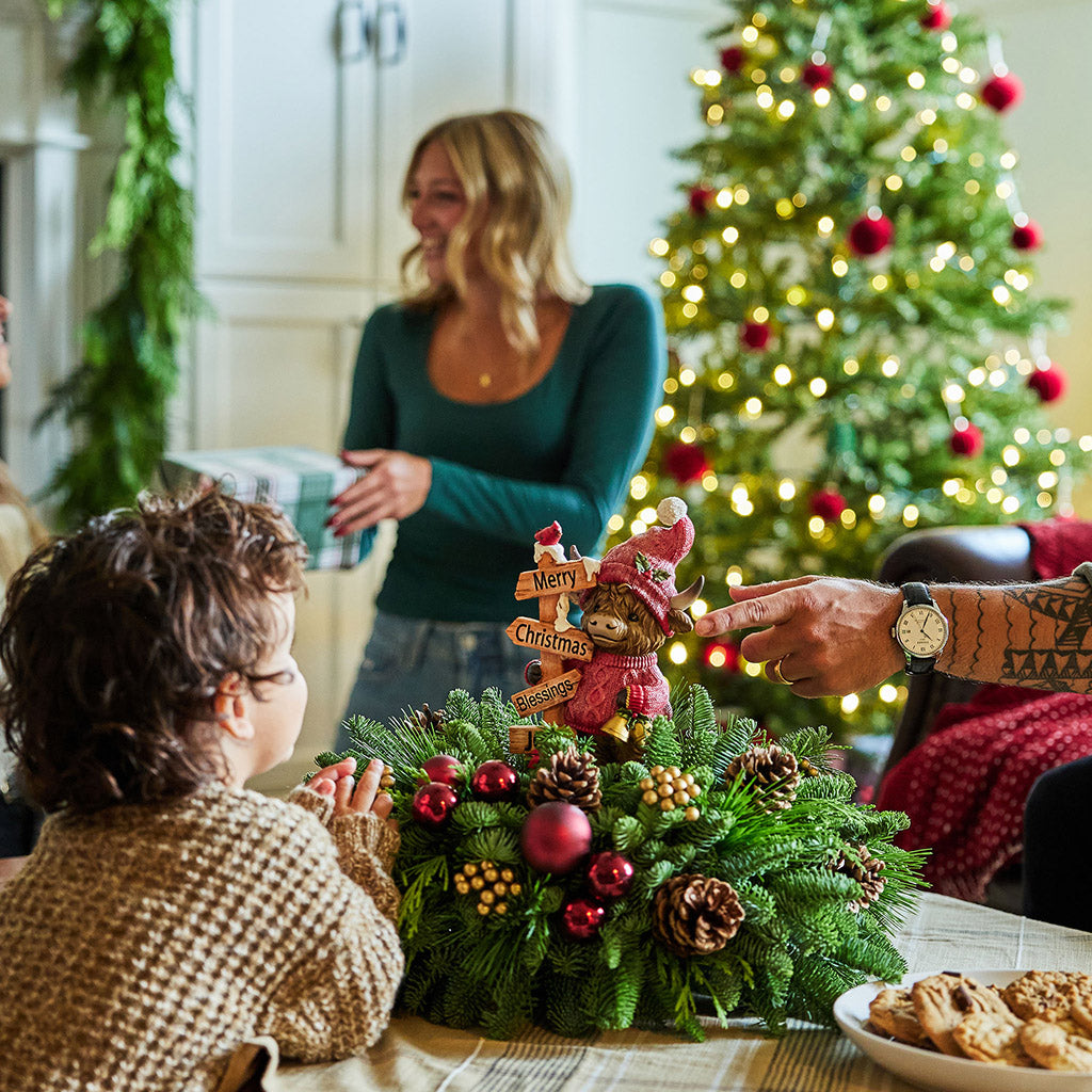 Family gathered around a Christmas tree with a decorated table and festive atmosphere.