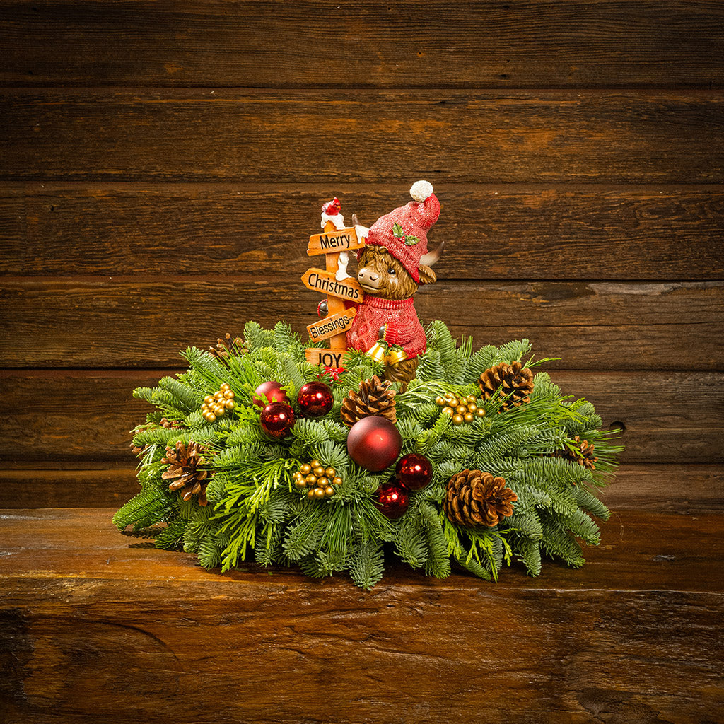 Decorative Christmas wreath with ornaments and a small bear figure on a wooden background