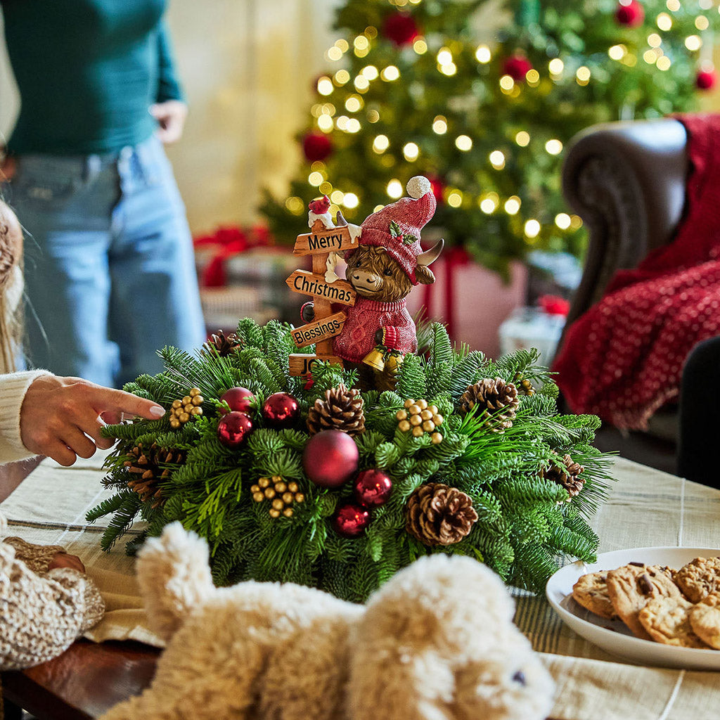 Decorative Christmas wreath with ornaments on a table, people in the background