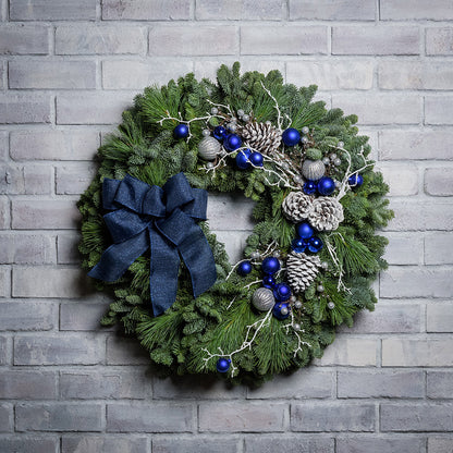 Blue and white decorations with blue bow on evergreen wreath