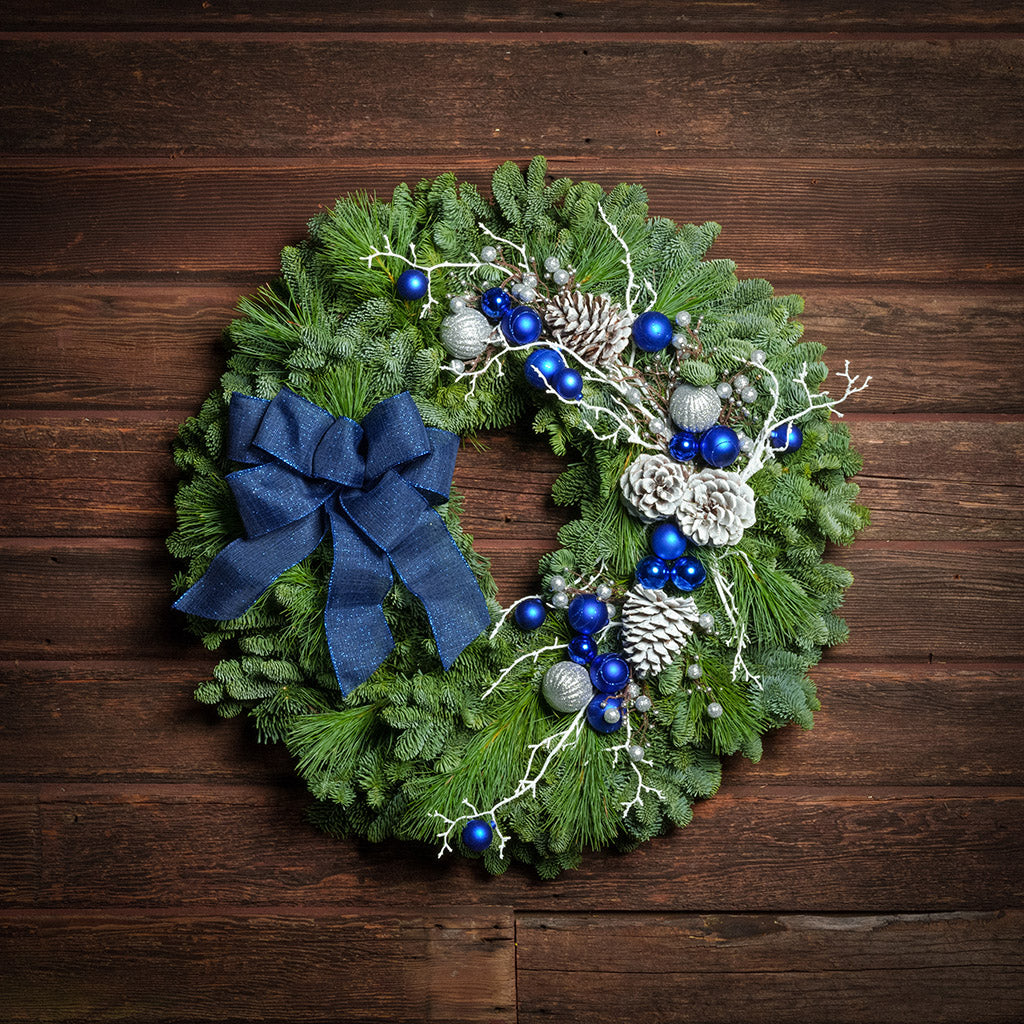 Blue and white decorations with blue bow on evergreen wreath