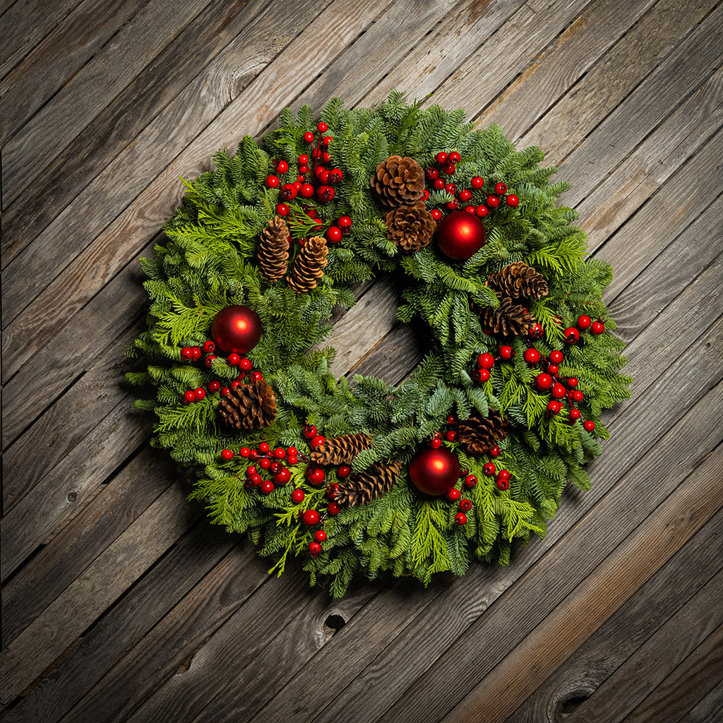 Christmas wreath with red berries and pine cones on a wooden background