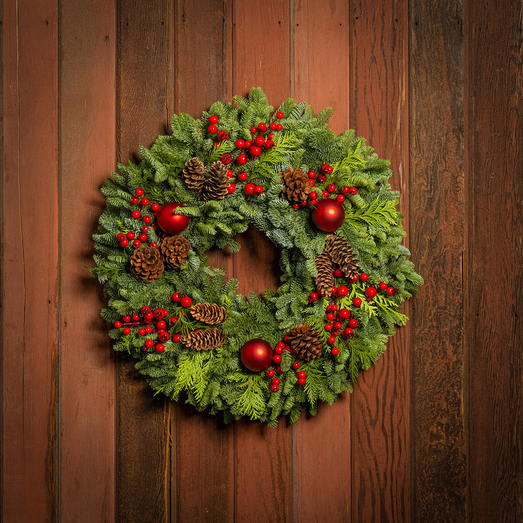Christmas wreath with red berries and pine cones on a wooden door