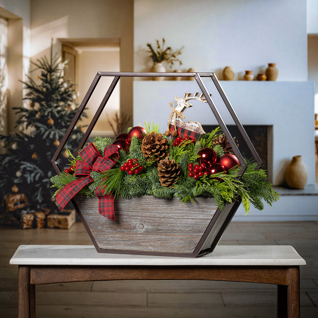 Decorative Christmas arrangement in a geometric wooden container on a table with a festive background.