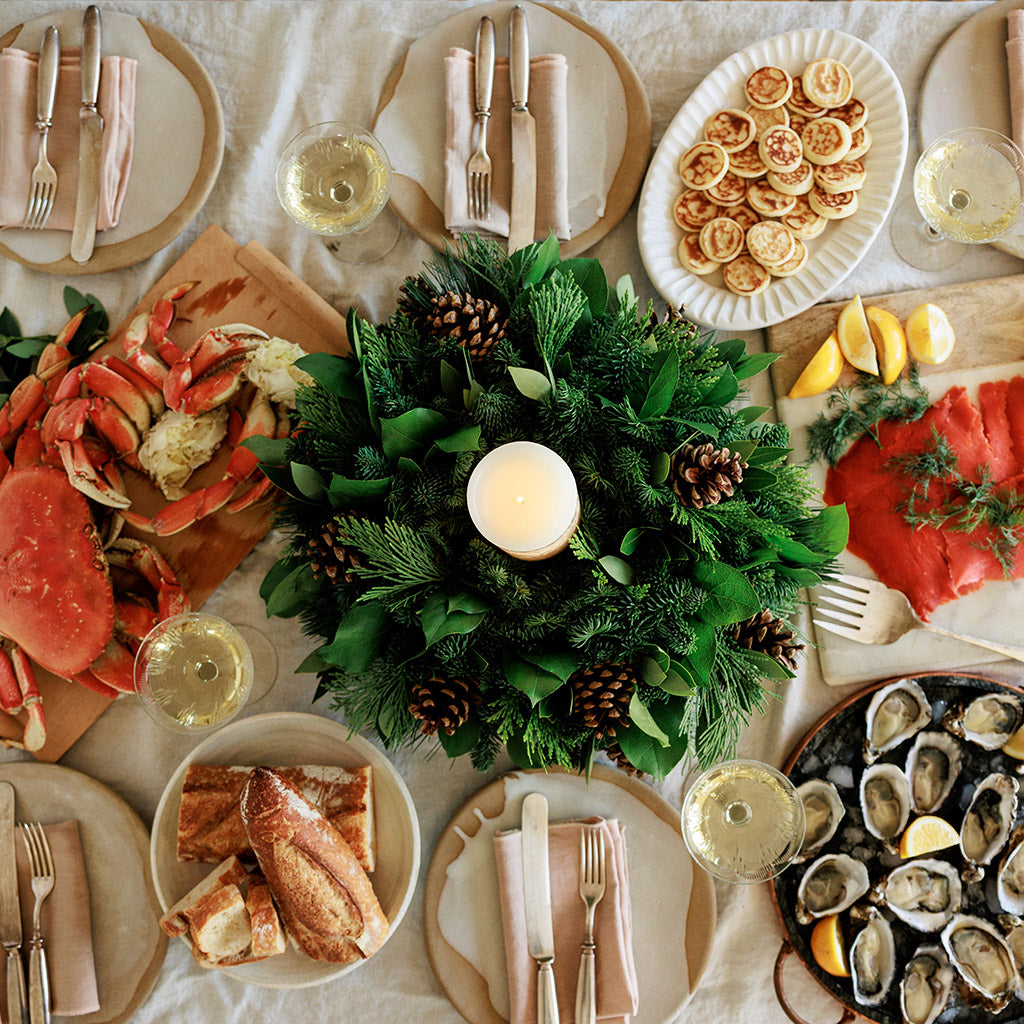 An arrangement of noble fir, cedar, white pine, salal, bay leaves, pinecones, and an ivory LED candle 