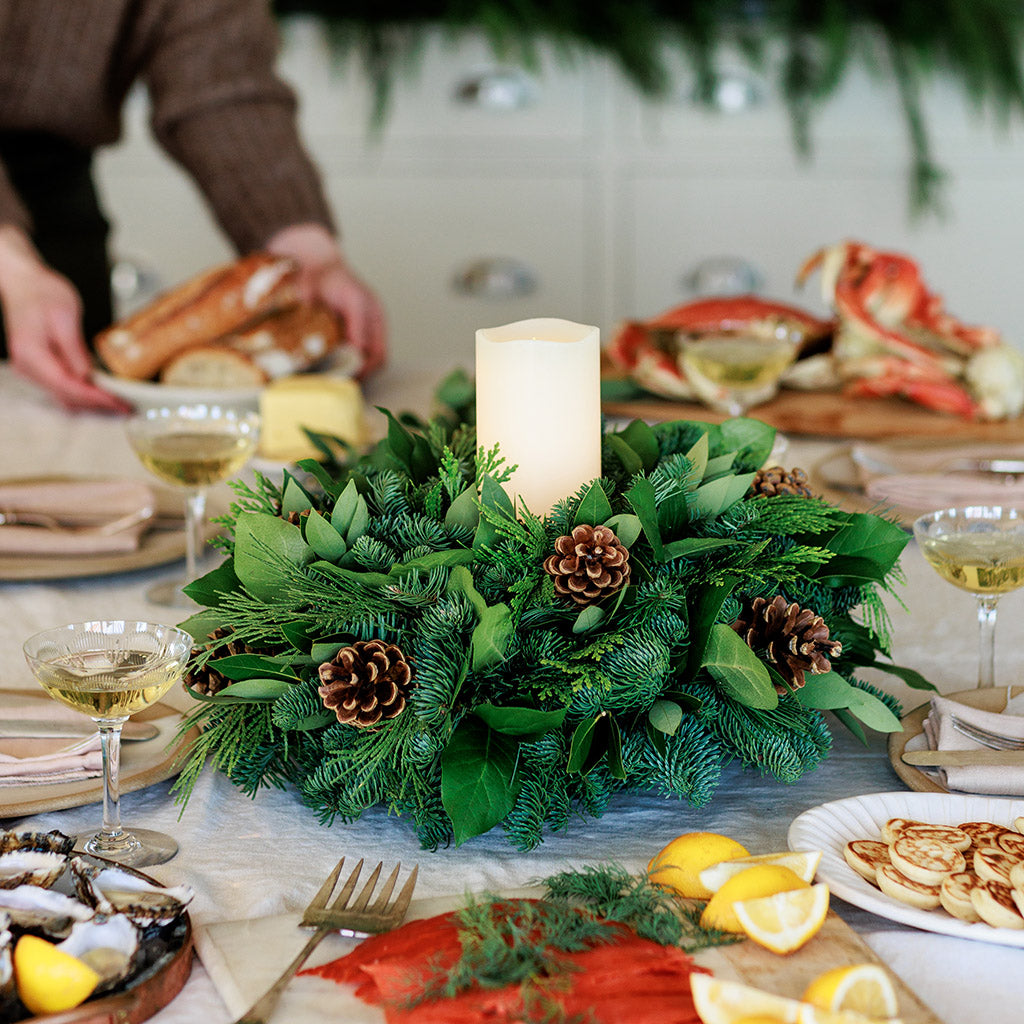 An arrangement of noble fir, cedar, white pine, salal, bay leaves, pinecones, and an ivory LED candle 