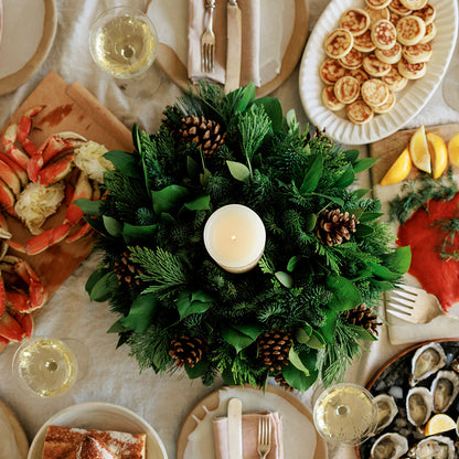 An arrangement of noble fir, cedar, white pine, salal, bay leaves, pinecones, and an ivory LED candle 