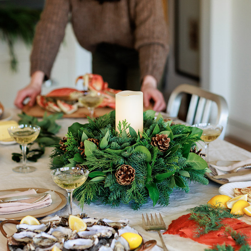 An arrangement of noble fir, cedar, white pine, salal, bay leaves, pinecones, and an ivory LED candle 