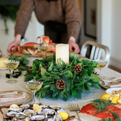 An arrangement of noble fir, cedar, white pine, salal, bay leaves, pinecones, and an ivory LED candle 