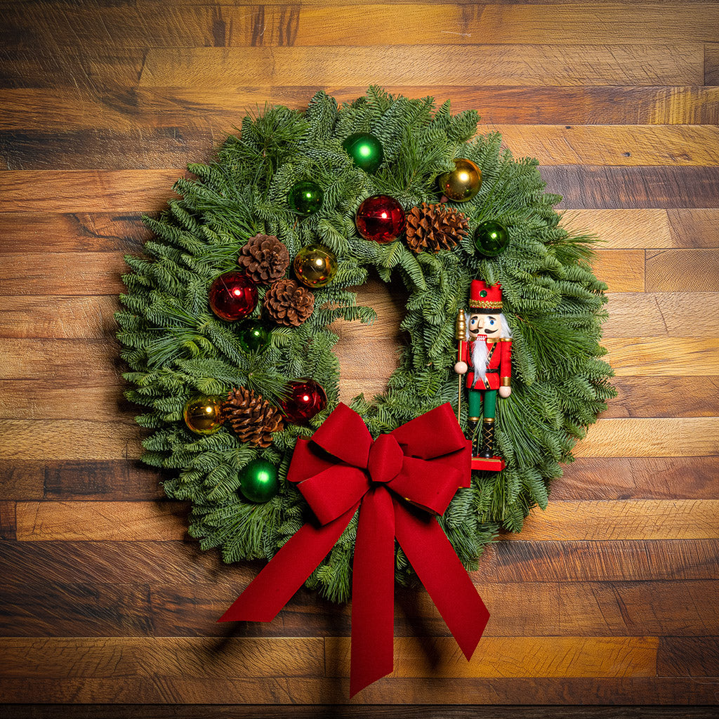 Decorative Christmas wreath with red bow and ornaments on a wooden surface