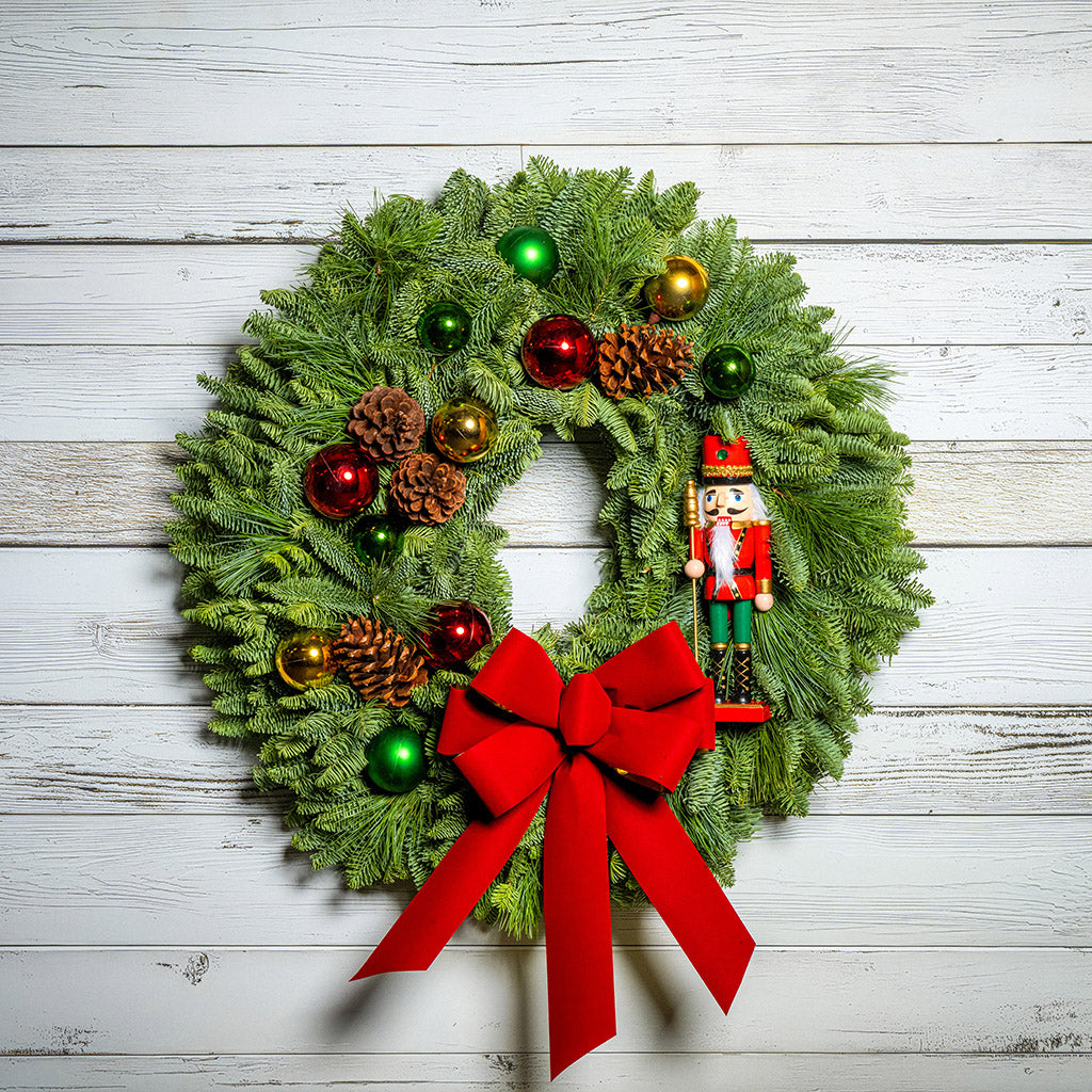 Christmas wreath with ornaments and a red bow on a wooden background