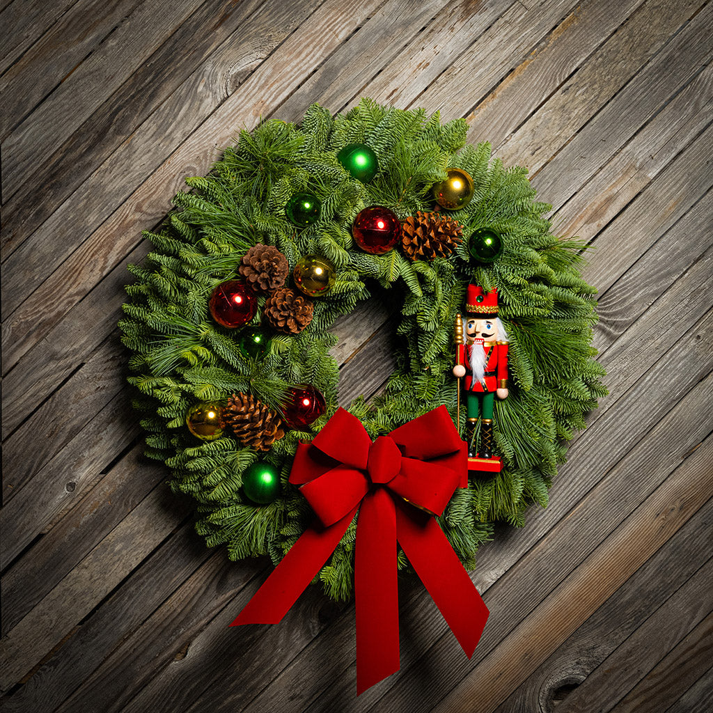 Christmas wreath with red bow and ornaments on a wooden background