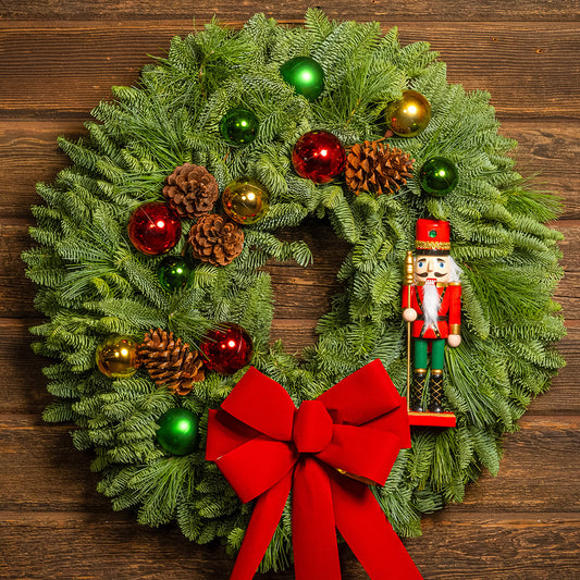 Christmas wreath with red bow, ornaments, and nutcracker on a wooden background