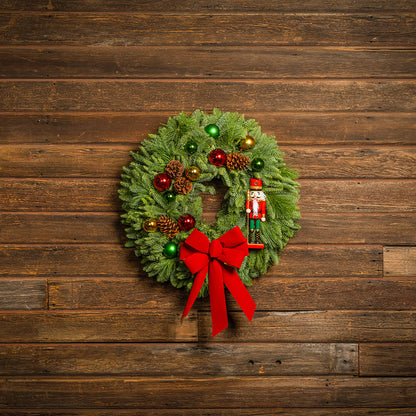 Decorative Christmas wreath with ornaments and a red bow on a wooden background