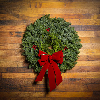 22" Christmas wreath of fir and cedar with three red berry clusters and a gold-backed red velveteen bow