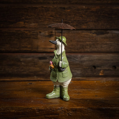 White duck in green rain gear holding a brown umbrella